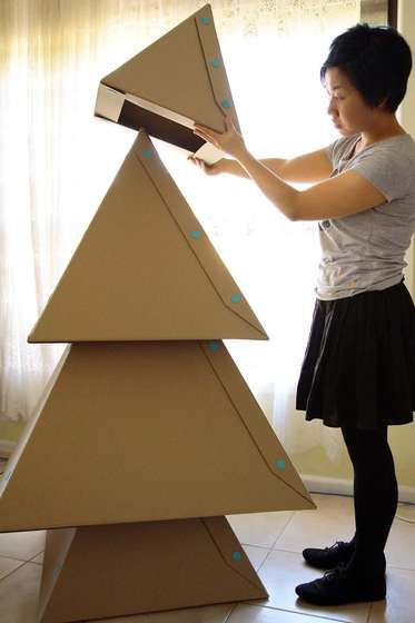 a woman standing next to a cardboard christmas tree