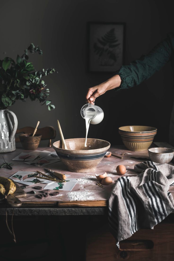 a person pouring batter into a bowl on top of a table