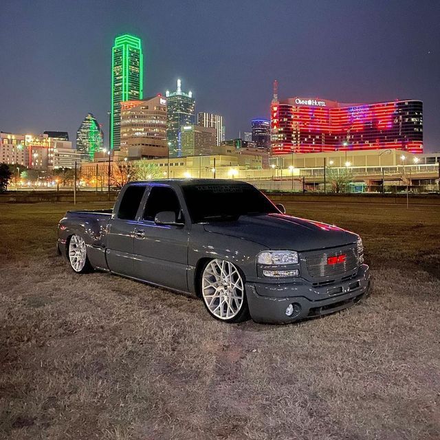 a black truck parked in front of a cityscape with buildings lit up at night