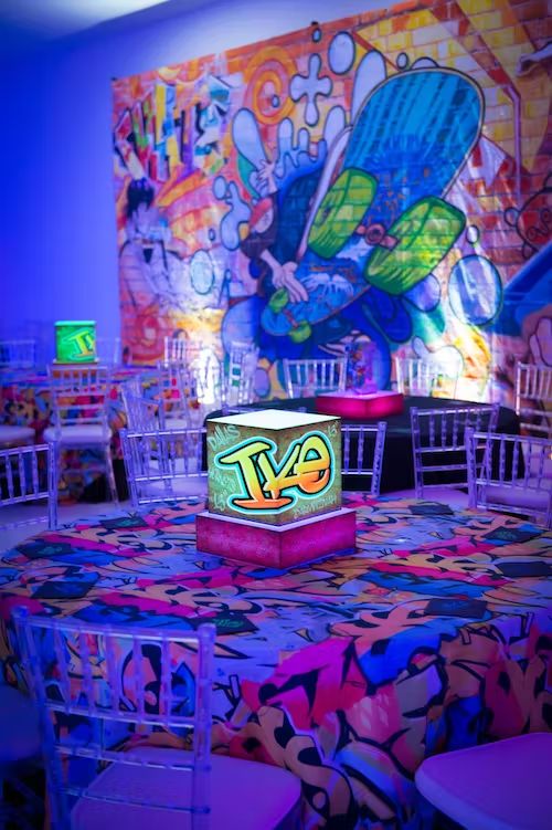 an illuminated cake sitting on top of a table in front of a colorful wall mural