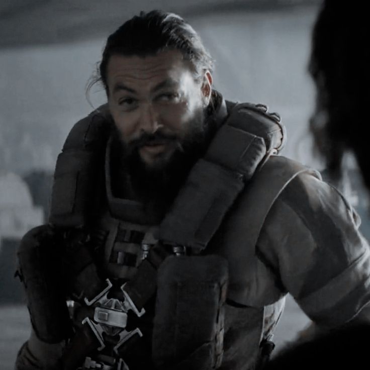 a man with a beard in a sci - fi suit standing next to another person