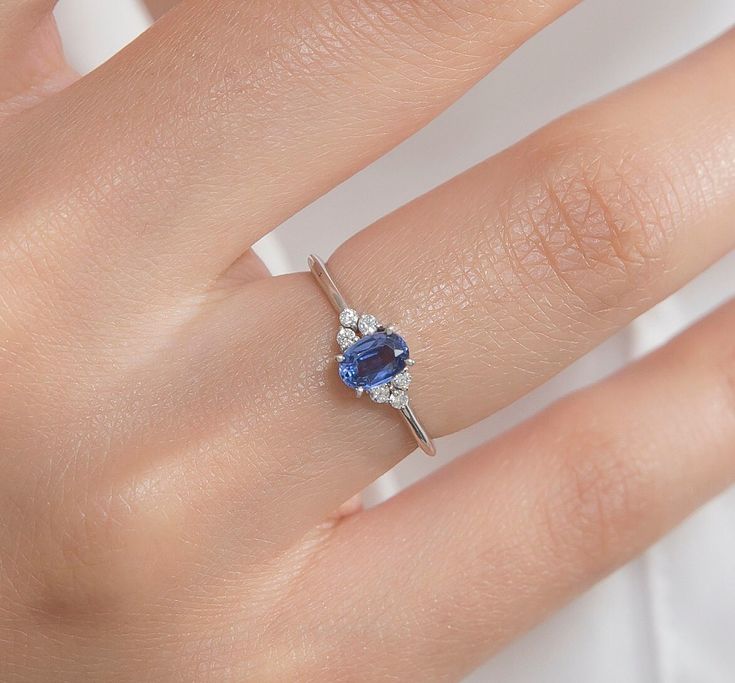 a woman's hand with a diamond and blue sapphire ring