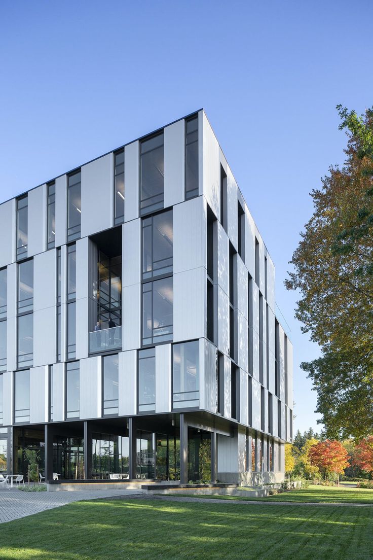 an office building with many windows and balconies on the front, along with green grass