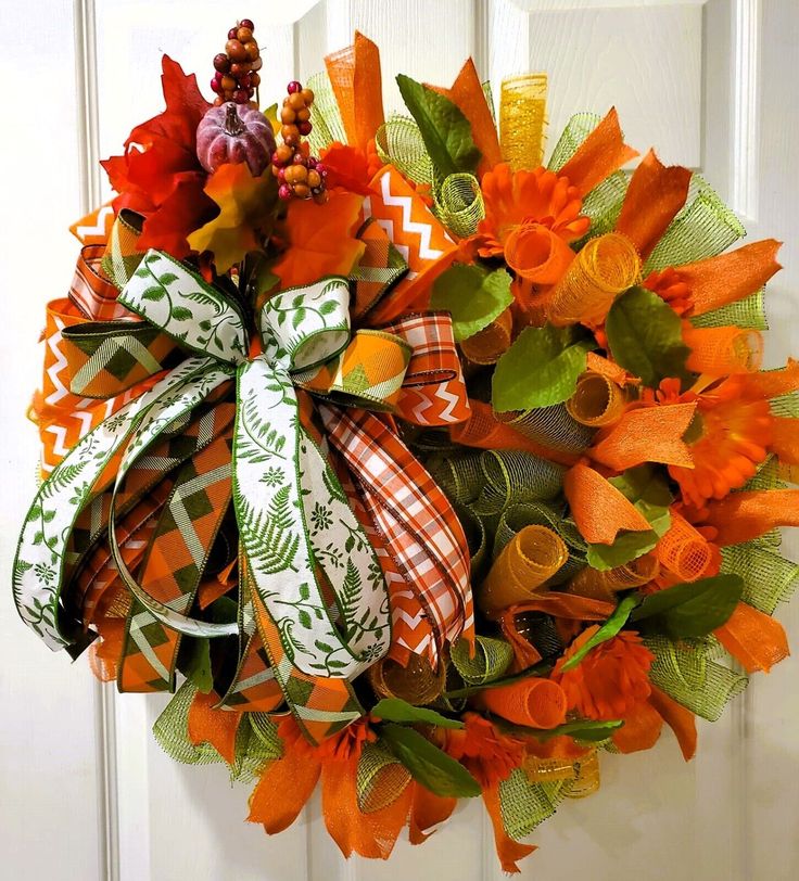 an orange and green wreath hanging on the front door