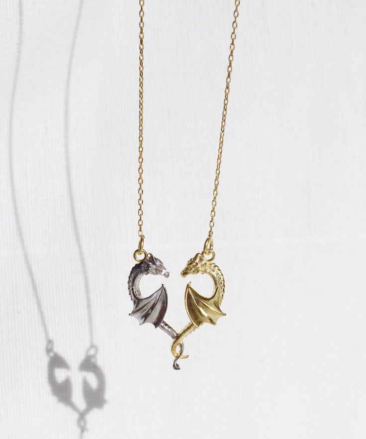 14K Gold Plated Dragon Heart Necklace  Embrace mythical love with this double dragon necklace! Crafted from sterling silver, two majestic dragons intertwine, forming a captivating heart. One dragon shines in gold, the other in silver, creating a stunning contrast. Elevate your style and let the symbolism of intertwined dragons tell your tale of love and unity. It is definitely a statement piece everyone needs in their jewelry collection! Features: * Materials: 925 Sterling Silver plated with 14K Gold Jewelry With Dragon Design, Fantasy Gold Jewelry With Dragon Design, Gold Fantasy Jewelry With Dragon Design, Gold Fantasy Necklace With Dragon Design, Fantasy Dragon Design Necklace, Symbolic Gold Dragon Jewelry, Gold Necklace With Dragon Design Collectible, Rose Gold Dragon Necklace, Gold Fantasy Dragon Necklace