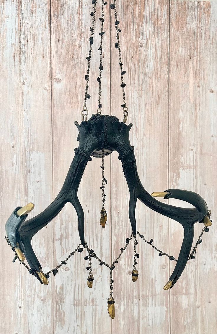 a black and gold chandelier hanging from a wooden wall with beads on it