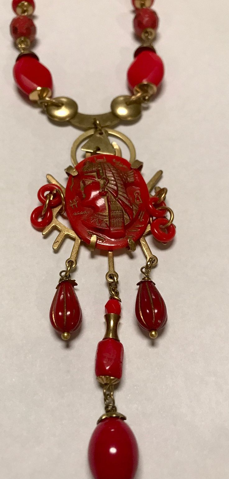 "An original Di Lelio Egyptian revival necklace.  Created with many vintage Czech glass elements in luscious red and brass detailing & elements-Eye catching sure to make a statement. Lenght-18.5\", the central detailed piece drop from the necklace  approx 4\" and is approx 1 1/4\" wide.  The central red glass Egyptian raised oval (piece is from the Neiger brother period circa v1920-30's.  All my pieces are signed." Red Pendant Necklace With Vintage Charm, Collectible Red Medallion Jewelry, Red Antique Collectible Jewelry, Antique Red Medallion Jewelry, Red Vintage Necklace With Charm, Antique Red Brass Jewelry, Vintage Red Necklace With Lobster Clasp, Antique Red Necklace With Large Pendant, Antique Red Necklaces With Vintage Charm