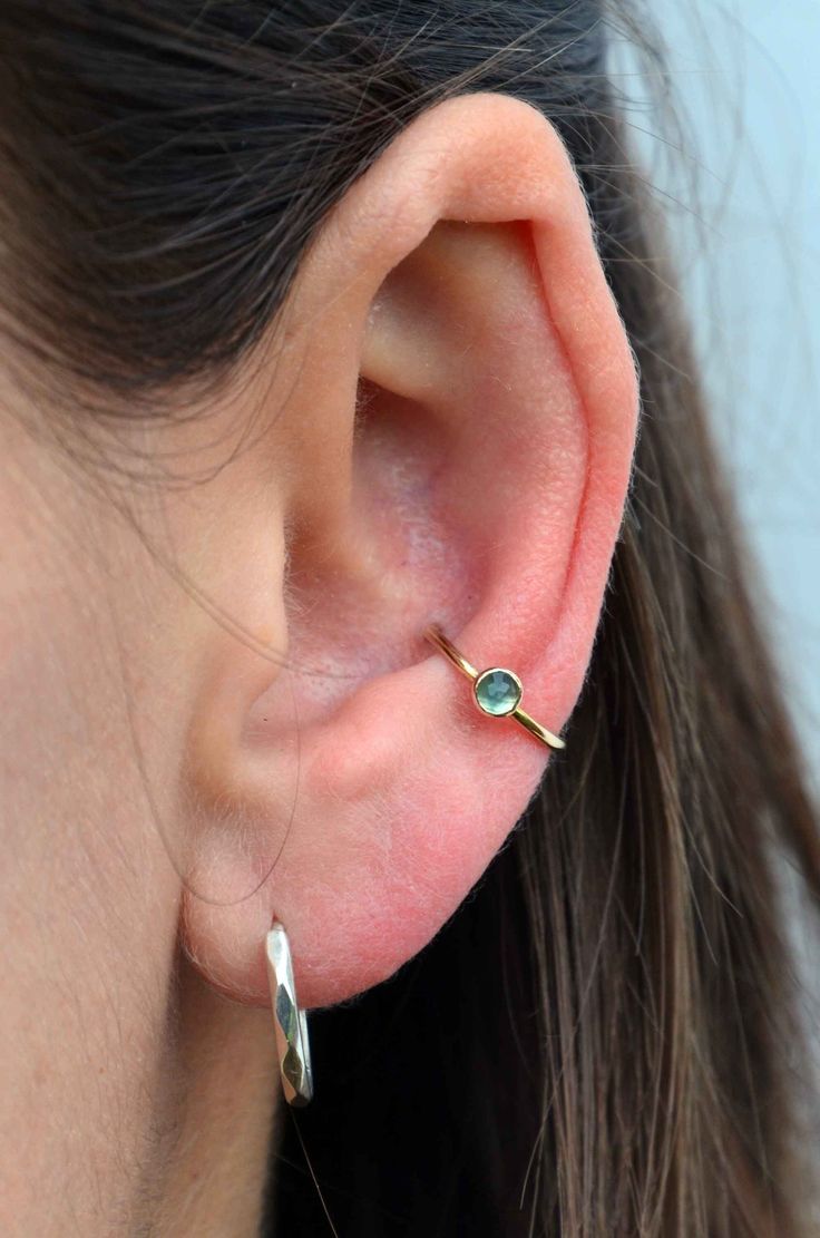 a close up of a person's ear with a small green stone in the middle