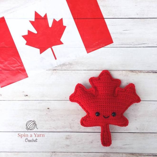 a crocheted maple leaf with the canadian flag in the background