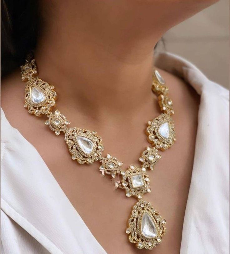 The elegantly handcrafted Gold polki necklace is based on silver and gold plating that celebrates the rich heritage of Indian jewelry. The silver polki necklace with matching polki earrings is a masterpiece that has a center uncut polki to give you a royal look. The bold and bright design of the necklace is perfect for all the beautiful brides to be! Pair this bridal necklace set with your ethnic or contemporary ensembles and create a look to remember. Necklace Closure - Adjustable Dori Earrings Closure - Push Back Style Tip - Looks best when worn with your royal whites, off whites, and gold. We love teaming this with classy chiffon sarees or zari silk sarees. We recommend styling with pastel solids or floral dresses in peachy pink, pistachio green, and pastel blue too. Customized orders t 22k Gold Teardrop Jewelry For Wedding, Gold Teardrop Jewelry Sets For Celebration, Festive Cutdana Jewelry For Diwali, Silver Kundan Temple Necklace For Celebrations, Ornate Kundan Meenakari Necklace, Yellow Gold Meenakari Bridal Necklace For Celebration, Bollywood Style Temple Necklace With Gota Work As Gift, Bollywood Style Temple Necklace With Gota Work, Yellow Gold Bridal Necklace With Meenakari For Celebration