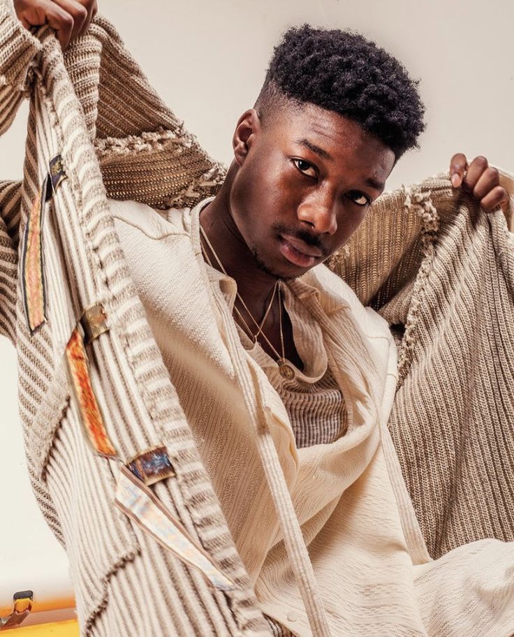 a young man is holding up some sweaters on his shoulders and looking at the camera