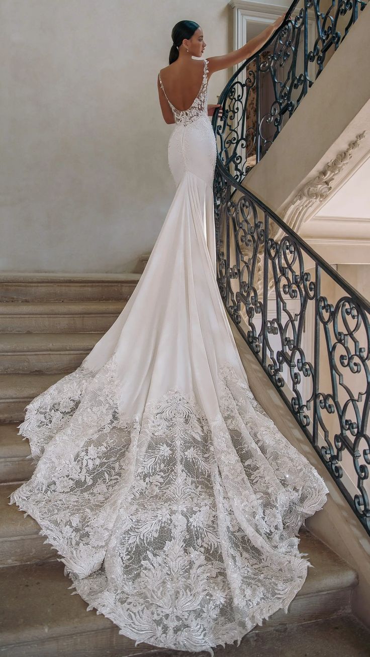 a woman in a wedding dress is standing on the stairs with her back to the camera