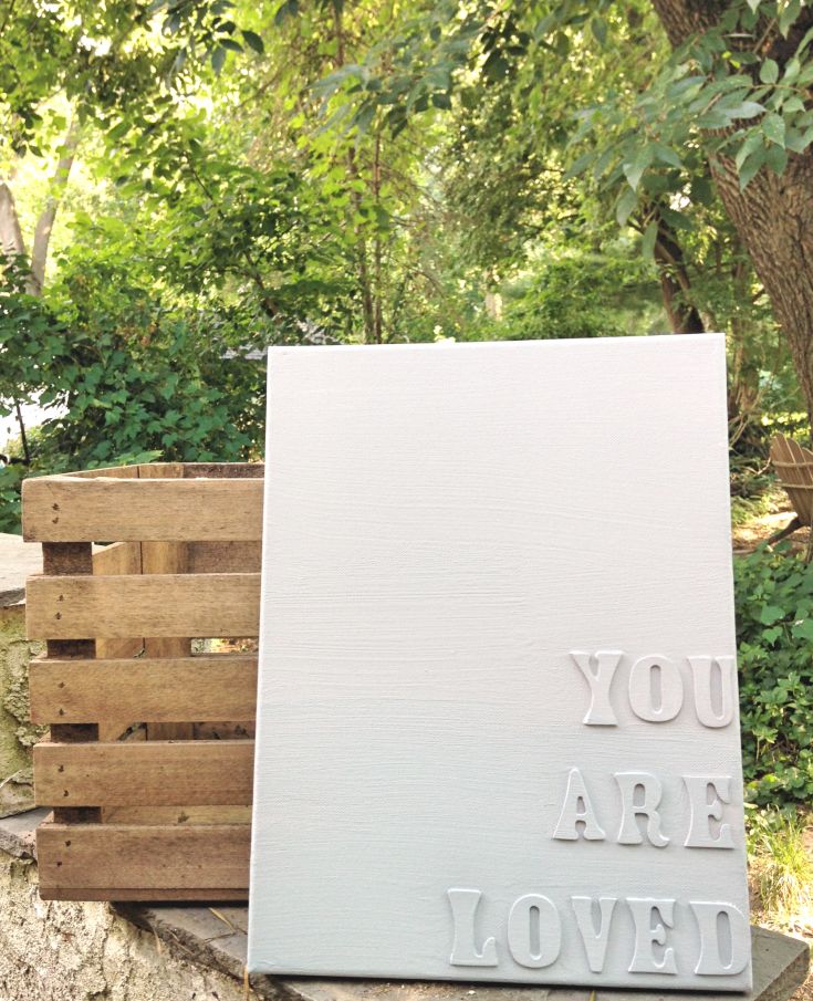 a sign that says you are loved next to some wooden pallets in the woods