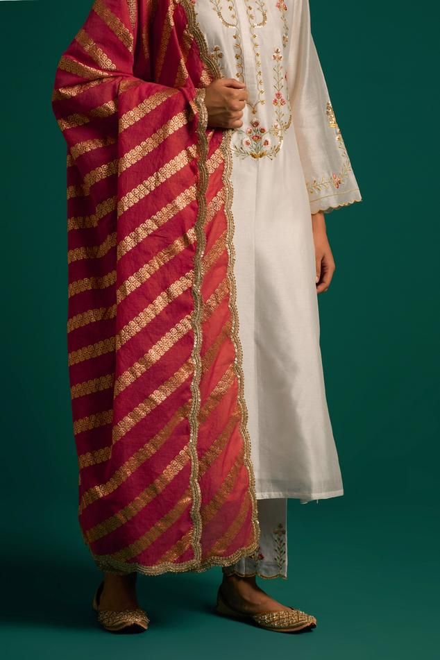 Off white silk chanderi kurta with placed thread floral embroidery and scalloped edges. Comes with matching pant and contrast dark pink chanderi dupatta.
Components: 3
Pattern: Embroidered
Type Of Work: Floral,Sequin
Neckline: Round
Sleeve Type: Full
Fabric: Kurta and Pant: Silk Chanderi, Dupatta: Chanderi
Color: Off White
Other Details: 
Model Height: 5ft 6inches wearing size S
Closure: Kurta: Front hook
Occasion: Mehendi and Haldi - Aza Fashions Chanderi Dupatta, White Kurta, Types Of Work, Kurta With Pants, Scalloped Edges, White Silk, Aza Fashion, Model Height, Dark Pink