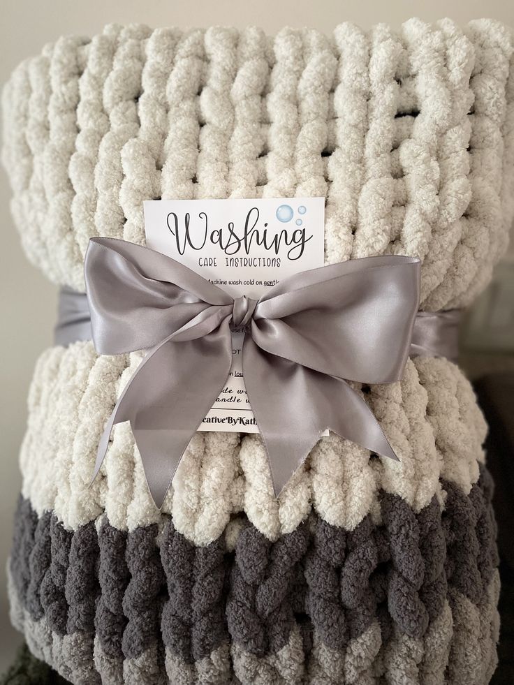 a stack of knitted blankets with a bow on top