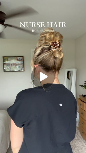 a woman standing in front of a bed wearing a black shirt with a flower in her hair