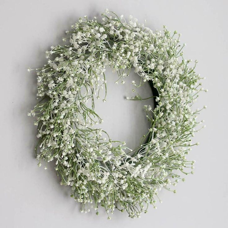 a wreath with white flowers hanging on the wall