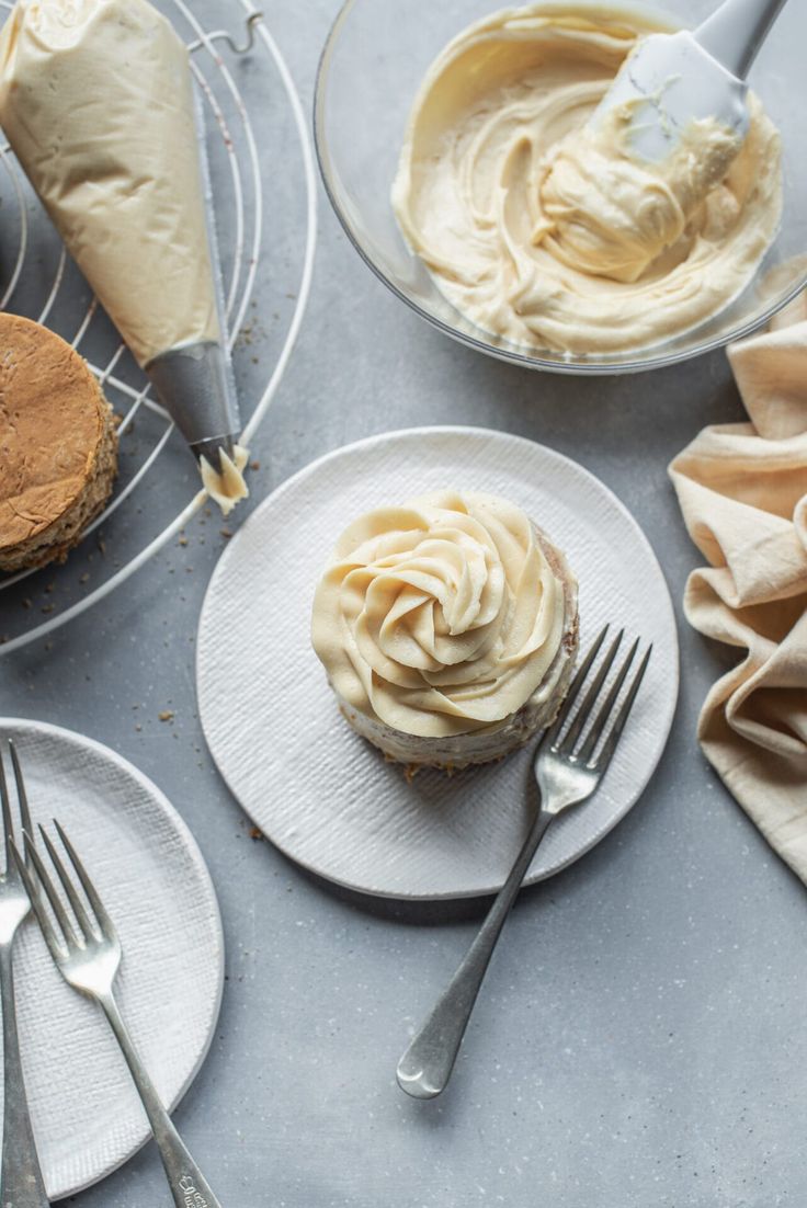 three plates with cupcakes and frosting on them next to forks, spoons and napkins