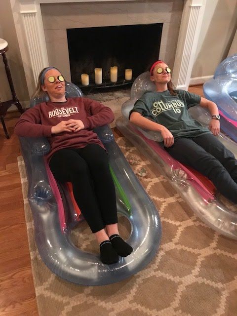 two people sitting on inflatable beds with candles behind them and one person wearing glasses