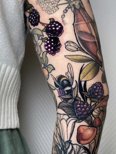 a woman's arm with fruit and flowers on it