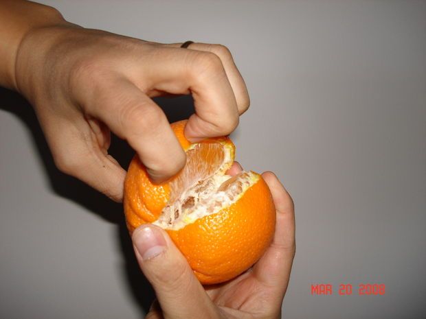 someone is peeling an orange with their hands on the top one and holding it in front of the other hand