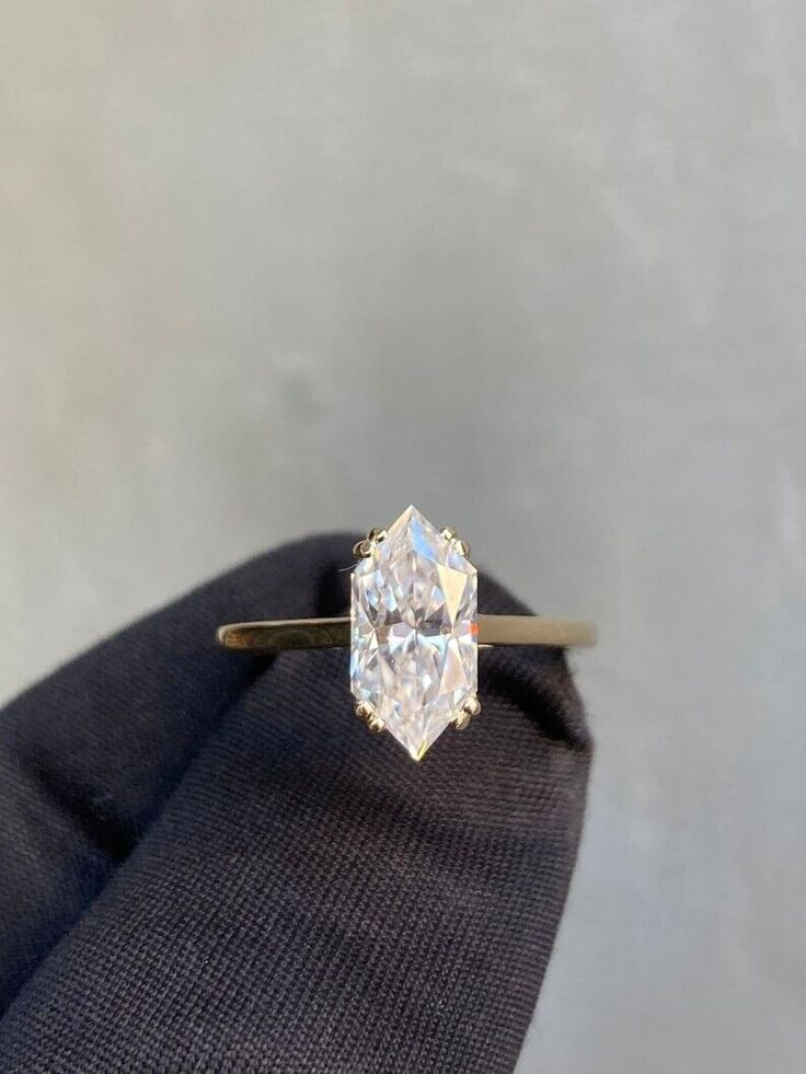 a diamond ring sitting on top of a black piece of cloth in front of a white wall