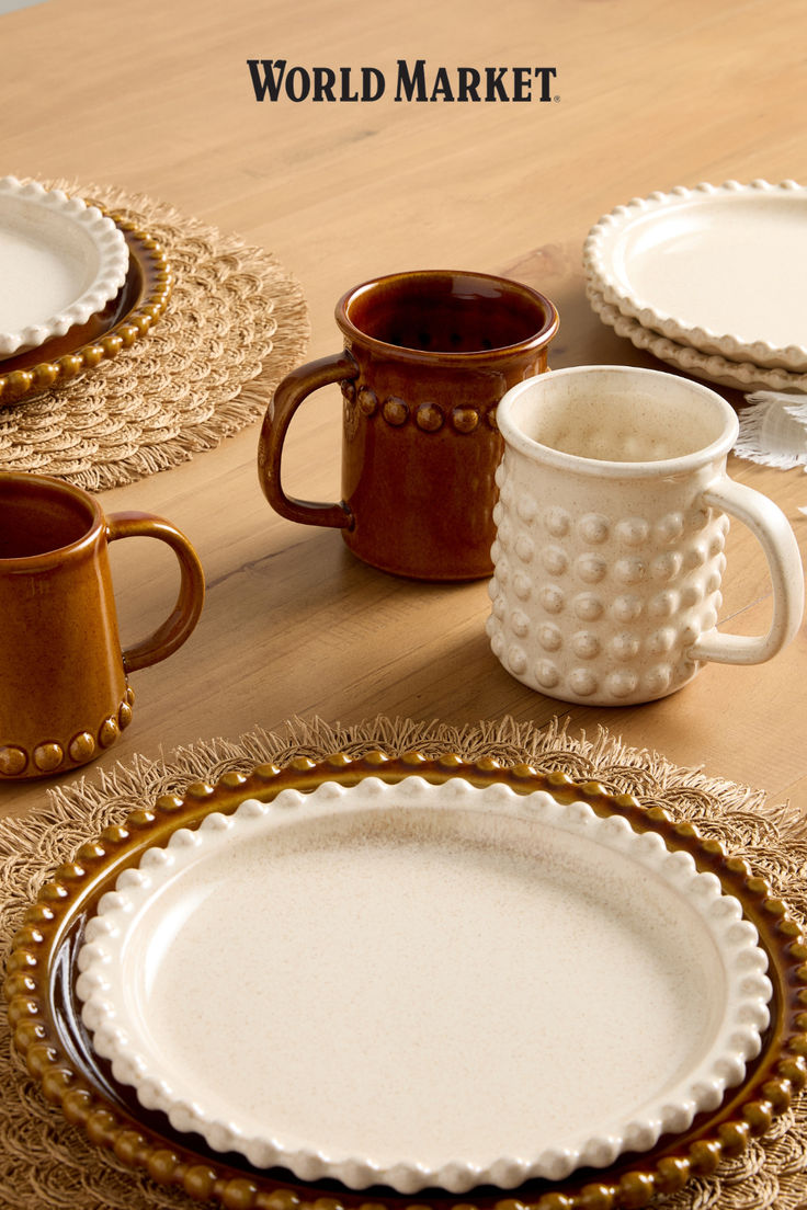 the table is set with plates, cups and mugs on it's placemats