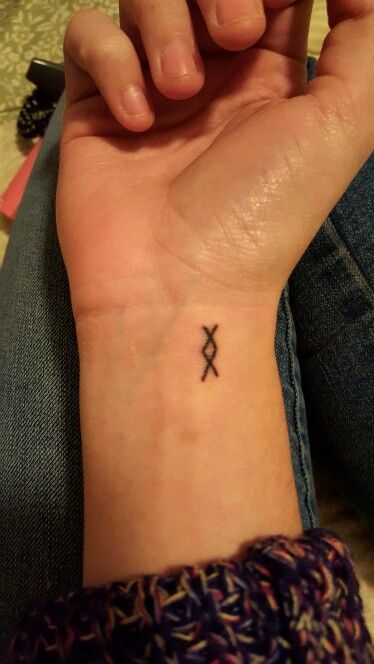 a woman's wrist tattoo with an x on the middle of her left arm