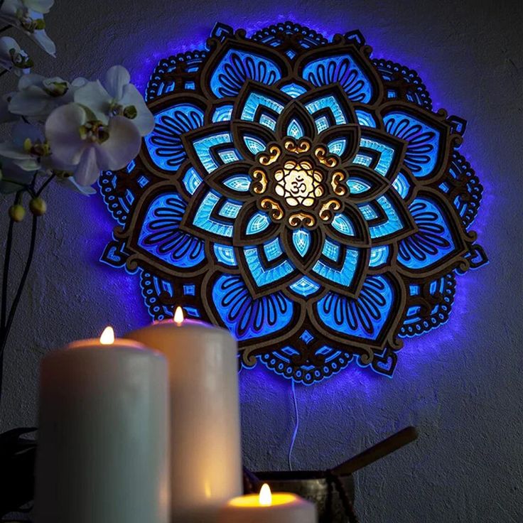 two candles are lit next to a wall decoration