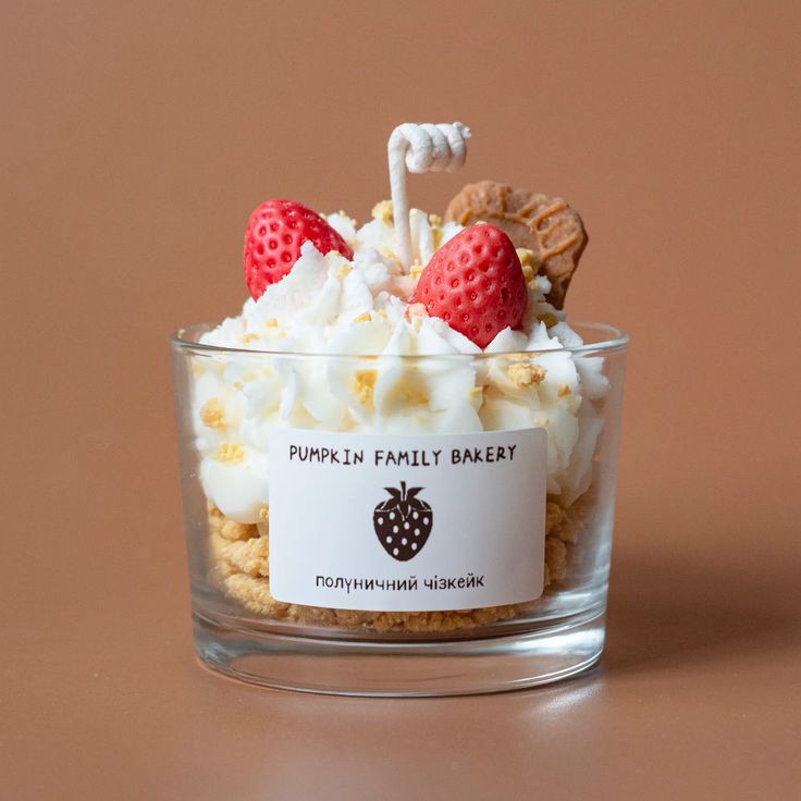 a glass bowl filled with whipped cream and strawberries on top of a brown table