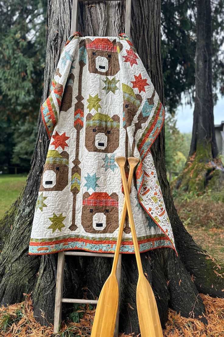 two wooden paddles leaning up against a tree with a bear quilt on the back