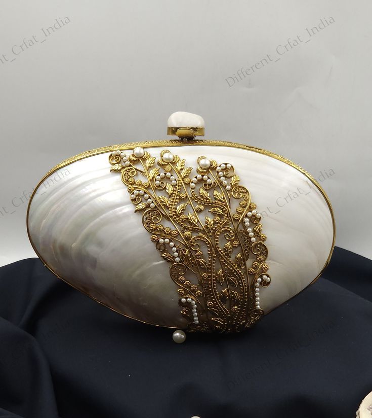 Handmade Sea Shell Minaudiere Purse Gold Filigree and Pearl Detail Shoulder bag, Mother of Pearl craftsmanship  Add a touch of elegance and sophistication to your evening ensemble with this exquisite handcrafted clutch bag. This stunning accessory features a natural Mother of Pearl shell, beautifully complemented by intricate gold filigree detailing and delicate pearl accents. The combination of these elements creates a luxurious and unique design that is sure to turn heads. Why You'll Love It: Handmade Luxury Pouch Clutch, Luxury Handmade Pouch Clutch, Luxury White Clutch For Reception, Luxury Openable Clutch For Wedding, Cream Handheld Clutch For Formal Occasions, Luxury Bags With Pearl Handle For Reception, Traditional Clutch With Pearl Handle For Formal Events, Traditional Clutch With Pearl Handle For Formal Occasions, Elegant Bags With Pearl Handle For Reception