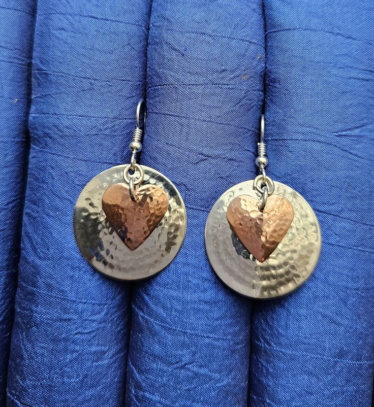 Hammered copper hearts over a one inch hammered sterling silver disc on a sterling ear wire. My unique hammering technique domes them a little and hardens the metal a little so they hold their shape well. Hammered Silver Earrings Made Of Copper, Hammered Silver Copper Earrings, Hammered Copper Earrings For Gift, Silver Hammered Copper Earrings, Heart-shaped Silver Copper Jewelry, Silver Heart-shaped Copper Jewelry, Hammered Round Disc Earrings As Gift, Hammered Round Disc Earrings For Gift, Metal Heart-shaped Earrings For Anniversary