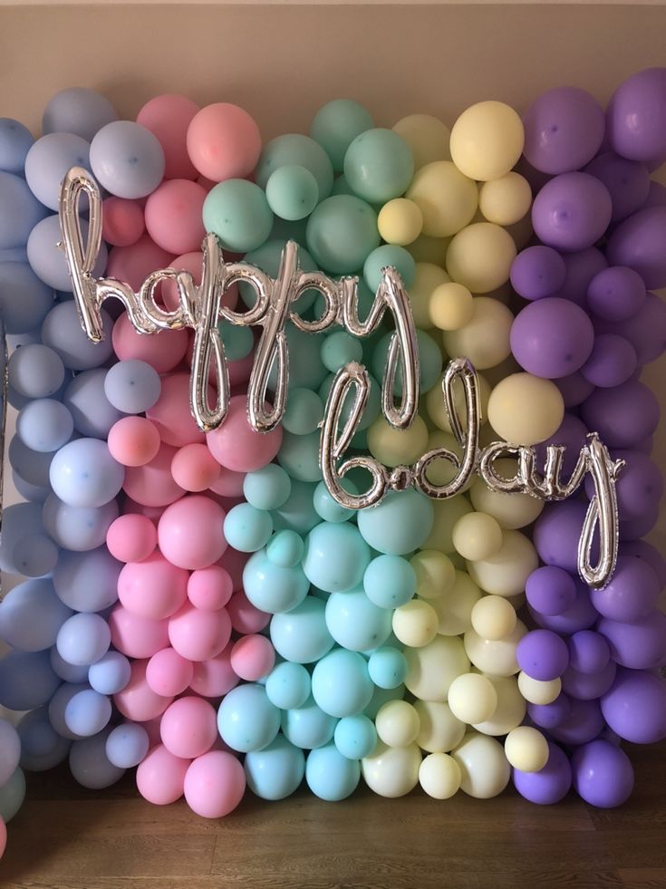 balloons and streamers with the words happy birthday written on them in front of a rainbow backdrop