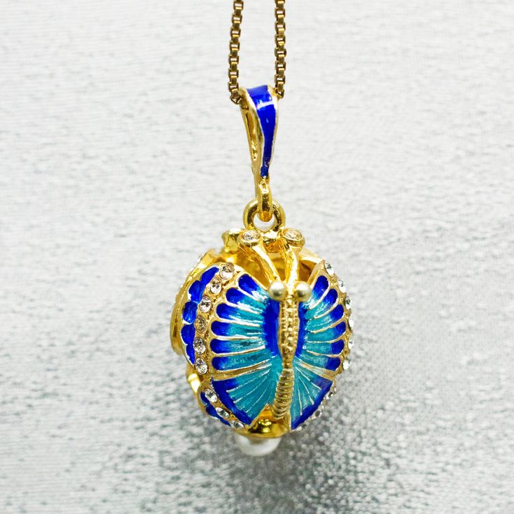 "Reticulated butterfly pendant, enameled and gold plated over solid sterling silver, designed  and made in our NJ shop in the tradition of  Faberge  jewelry. Two butterflies are connected by the ends of the wings and by antennas, creating the egg shaped piece. The wings are covered by sky-blue and cobalt-blue enamel and the ends of the wings are decorated with clear crystals. A pearl at the bottom of the pendant completes the design.   The pendant is about 0.8\" (  20 mm ) without the bail  - 1. Blue Enamel Locket Jewelry, Blue Enamel Oval Pendant Jewelry, Blue Oval Enamel Necklace, Gold Enamel Jewelry With Detachable Pendant, Gold Enamel Jewelry With Butterfly Charm, Blue Charms Jewelry Gift, Oval Enamel Necklace For Gift, Elegant Enamel Jewelry Keepsake, Oval Enamel Jewelry For Gift