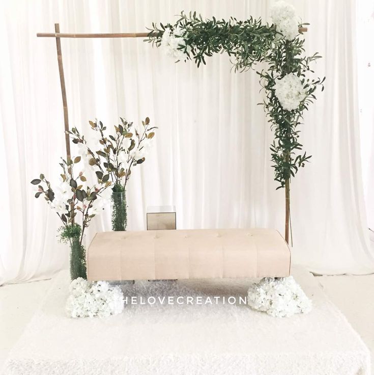 an arrangement of flowers and greenery is displayed on a white carpeted stage for a wedding ceremony