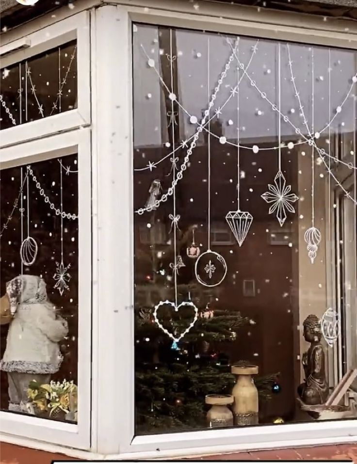 a teddy bear sitting in the window of a store with christmas decorations hanging from it's windows