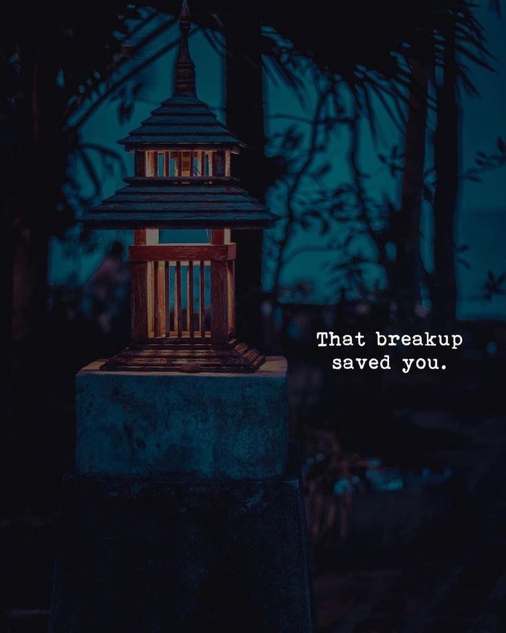 a lit up lantern sitting on top of a cement block in front of some trees