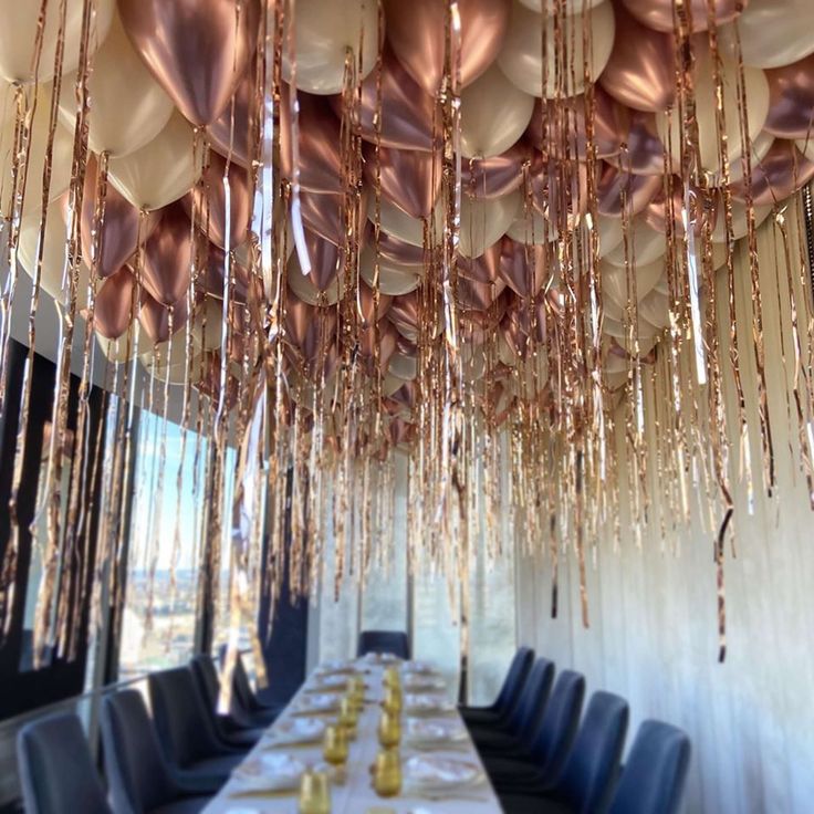 a long table with many balloons hanging from the ceiling