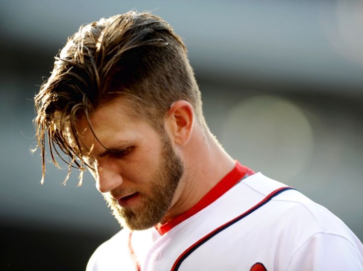 a close up of a baseball player wearing a uniform and looking down at his cell phone