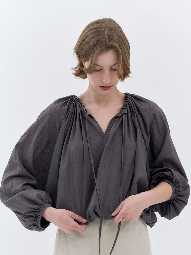 This loose fitting blouse has basic round neckline and wide long sleeves. It is accentuated with adjustable shirred string detail at neckline.  - Cotton and nylon blend fabric- Sheer, lightweight texture- Casual raglan sleeves - Smocked detail at cuffs- Romantic, feminine feel Billowy Long Sleeve Blouse With Elastic Sleeves, Long Sleeve Tops With Elastic Sleeves For Daywear, Billowy Long Sleeve Blouse With Gathered Sleeves, Billowy Peasant Top With Elastic Sleeves For Fall, Fall Billowy Peasant Top With Elastic Sleeves, Fall Tops With Gathered Sleeves For Daywear, Billowy Long Sleeve Chic Peasant Top, Spring Long Sleeve Top With Gathered Neckline, Chic Billowy Long Sleeve Peasant Top