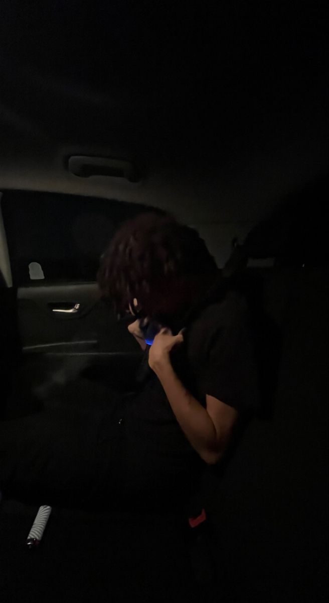 a woman sitting in the back seat of a car talking on her cell phone at night