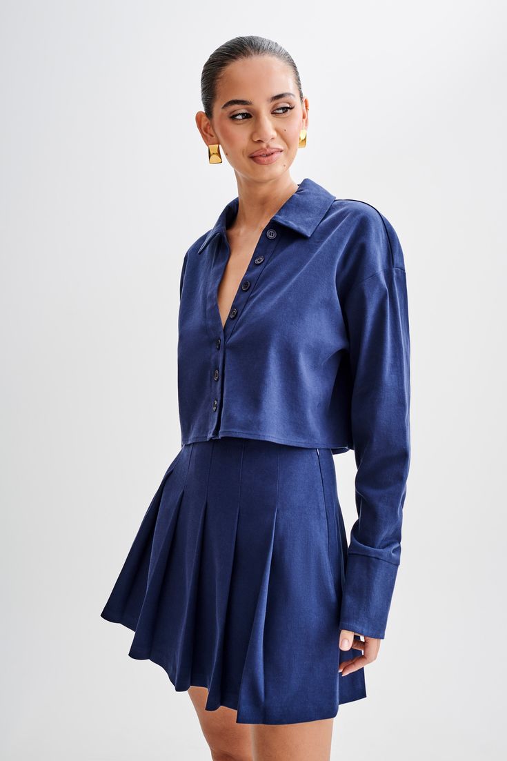 Buttoned and ready. Introducing the JULIANNA Cotton Button Up Shirt in Navy, a versatile staple for every wardrobe. With its collared neckline and functional center front placket with button closure, this shirt exudes timeless sophistication. The cropped length adds a modern twist, while long sleeves and functional cuffs offer both style and practicality. Crafted from breathable, unlined cotton, it ensures comfort all day long. Complete with a back inverted box pleat and back yoke details, this shirt combines classic elements with contemporary flair. Whether dressed up the Julianna Cotton Pleated Mini Skirt or dressed down with jeans, the Julianna Cotton Button Up Shirt is a versatile piece that effortlessly elevates any outfit. Chic Button-up Cropped Shirt With Button Closure, Classic Single-breasted Button-up Top, Classic Single Breasted Button-up Top, Blue Collared Cropped Shirt For Work, Collared Cropped Shirt For Day Out, Chic Fitted Cropped Shirt With Collar, Single Breasted Relaxed Fit Tops For Business Casual, Classic Cropped Button-up Shirt With Button Cuffs, Fitted Long Sleeve Cropped Shirt For Day Out