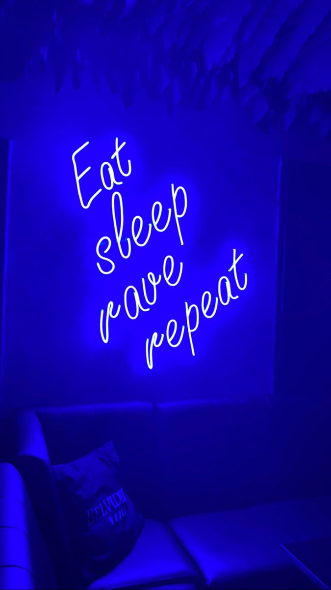 a neon sign that says eat sleep rave repeat on the wall next to a couch