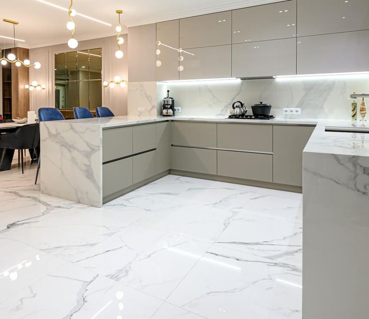 a large kitchen with marble counter tops and white walls, along with blue chairs in the background