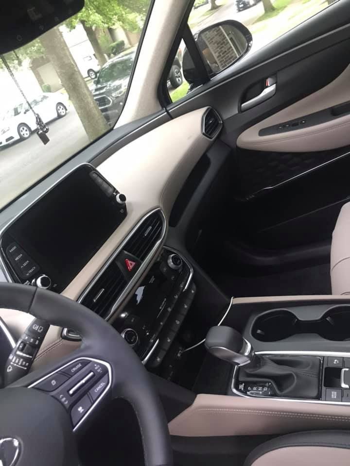 the interior of a car with an electronic device in the center console and steering wheel