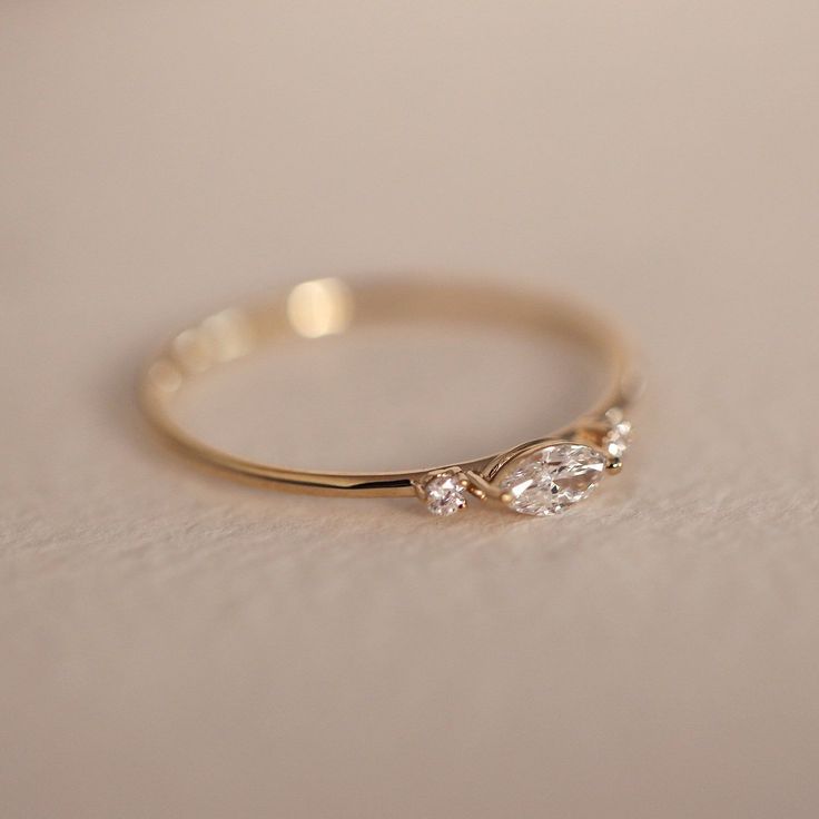 a gold ring with two diamonds on it sitting on a white tableclothed surface