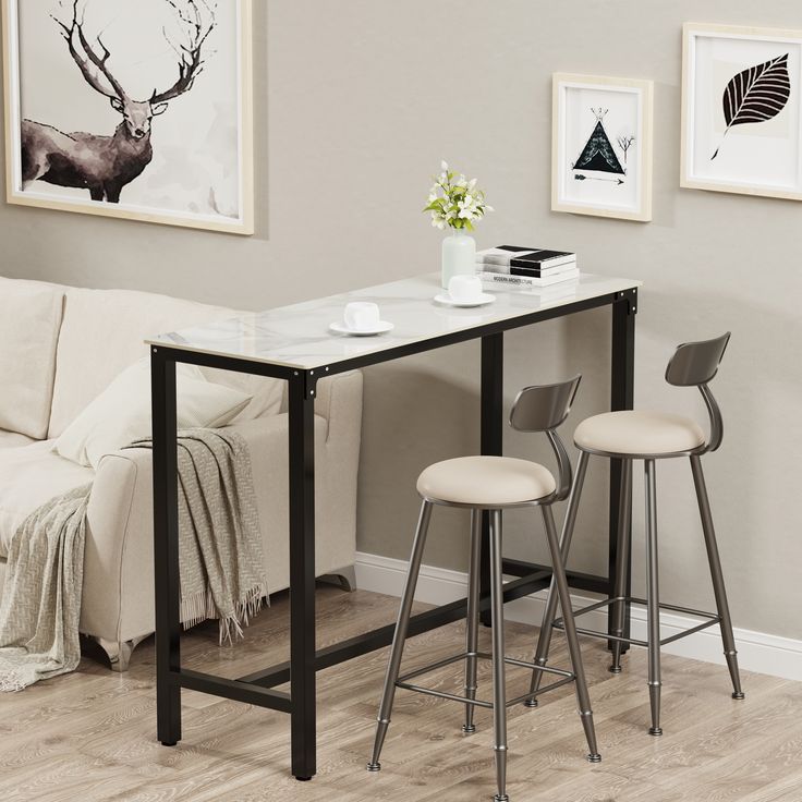 a small table with two stools next to it in front of a white couch