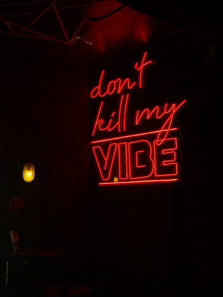 a red neon sign that says don't kill my vibe on the side of a building