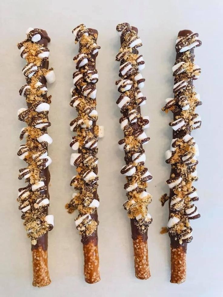 four different types of candy sticks with toppings on them, lined up against a white background